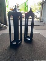 Pair of tall rectangular black metal lanterns on floor