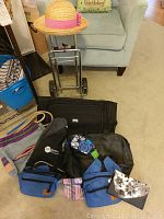 Full view of all items including bags, wallet, luggage roller, and hat