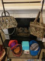 Photo showing two tapestry travel bags hanging and several plastic storage bins with decorative woven hats nearby.