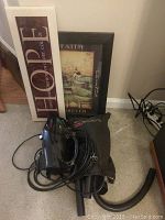 Turbovac 800 vacuum cleaner with strap and power cord, positioned on carpet near two framed pictures that lean against the wall.