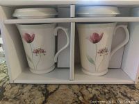 Boxed set of two Hankook mugs with lids inside original packaging placed on countertop.