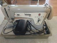 Off-white Singer Fashion Mate 506 sewing machine on a beige base with black foot pedal and cords in view.