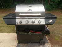 Full front view of the GrillMaster propane grill showing the four control knobs, black side shelves, and two wheels.