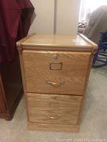 Front view of a wooden two-drawer filing cabinet with metal handles and lock on top drawer.