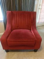 Front view of burgundy upholstered accent chair showing channel tufting and squarish dark wooden legs