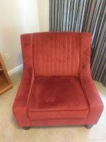 Front view of the burgundy upholstered chair showing its tall backrest with vertical stitching and cushion seat.