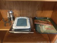 Wooden shelving with a Coca-Cola metal serving tray, stack of assorted picture frames, a small lantern, and a pair of horseshoes