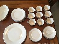 Full set of Lenox china including cups, saucers, and plates laid out on table