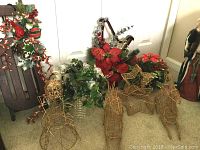 Group of holiday decorations including a sleigh, greenery, poinsettias, angel, deer and gold wire pieces.