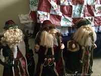 Three standing decorative Santa figurines about 25 inches tall, with porcelain faces and hands, arranged together