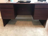 Front view of the dark stained wood desk showing two drawers on each side with no visible handles.