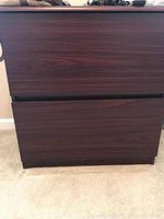 Front view showing the two drawer file cabinet with dark finish and handle grooves.