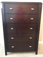Front view of the five drawer chest showing dark stained wood and silver knobs on each drawer.