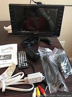 Front view of SuperSonic SC-499 LCD digital TV receiver with protective plastic on screen and displayed accessories including remote, power adapter, cables, and manual.