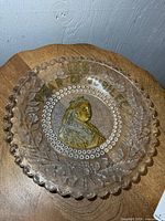 Full view of pressed glass plate showing size, scalloped rim, and central portrait