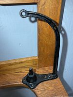 Side view of curved cast iron arm and top loop of string holder frame