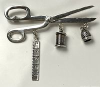 Front view of sterling silver scissors brooch with three sewing charms