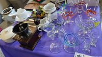 Group shot showing coffee grinder, glass bowls with colored swirls, cordial glasses, white ceramic pieces and fruit ornament