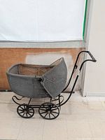 Full left view of wicker pram showing basket, wheels and handle