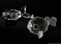Two crystal fish figurines on dark surface
