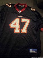 Front view of jersey showing #47, Buccaneers wordmark and autograph marks