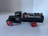 Right side view of black Premier Gasoline tanker truck with red wheels