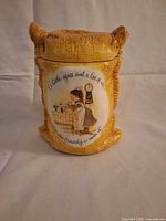 Front view of yellow ceramic Holly Hobbie jar with lid on