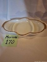 Top view of divided milk glass dish showing gold rim and handles
