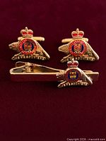 Front view of pair of cufflinks and tie bar showing crest details and enamel colors