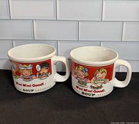 Front view of both Campbell’s soup mugs showing graphics