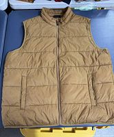 Front view of tan puffer vest showing zipper and pockets