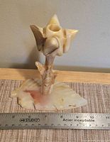 Front view of carved calcite tulip candle holder with ruler for scale