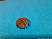 Full coin view on blue background showing obverse design and legends.