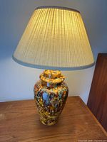 Lamp lit, showing full lamp with shade on wooden surface