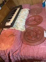 All five pink glass serving plates displayed on bed, showing overall sizes and styles
