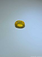 Loose yellow oval fire opal on plain background