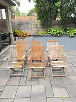 six teak folding armchairs arranged on patio
