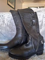 Side profile of both boots showing leather upper, ankle buckle, and overall height