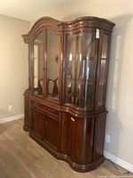 Front view of dark wood buffet and hutch showing glass doors and curved glass ends