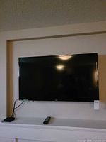 RCA wall-mounted television with Apple TV box and remote visible below