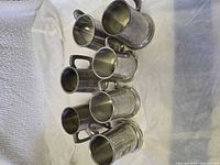 Seven pewter tankards grouped together showing overall condition and quantity