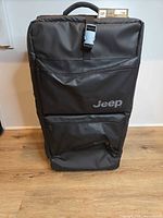 Front view of black Jeep rolling duffel showing logo and zip pockets