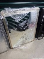 Front view of rectangular LED mirror wrapped in protective plastic