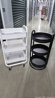 White rolling cart and black round stand side by side showing overall design and scale