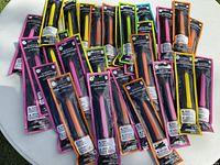 All 28 sealed glow stick packs spread on table showing color variety