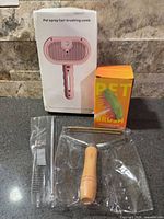 Boxed pet spray hair brushing comb, boxed spray massage brush, metal comb in sleeve, wooden handle rake on countertop