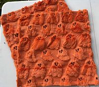 Two orange pillow covers displaying tufted ghost motif on textured knit front