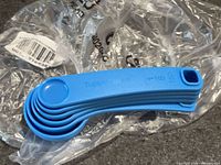 Stacked blue Tupperware measuring spoons on top of clear bag