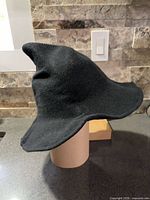 Side profile of black knit witch hat on stand