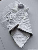 Entire security blanket showing bear head, white dimple front, grey underside and packaging